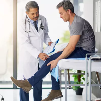 Doctor checking a male patient's knee.