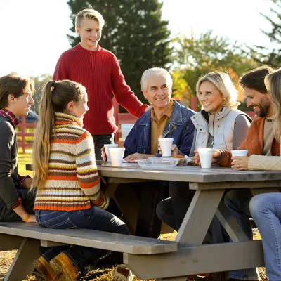 Family sitting outside at a picnic table having a meal.