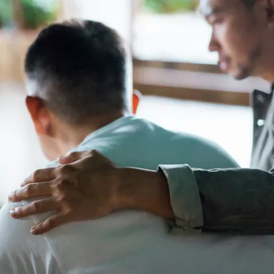 A young man having his arm around a mature man