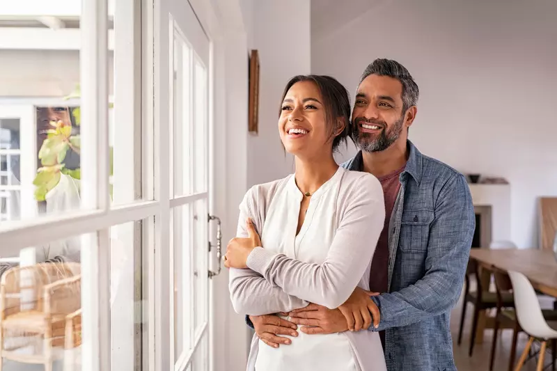 Man and woman smiling and looking out of window. 