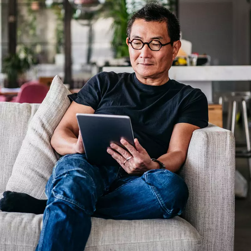 An asian man reading in his living room