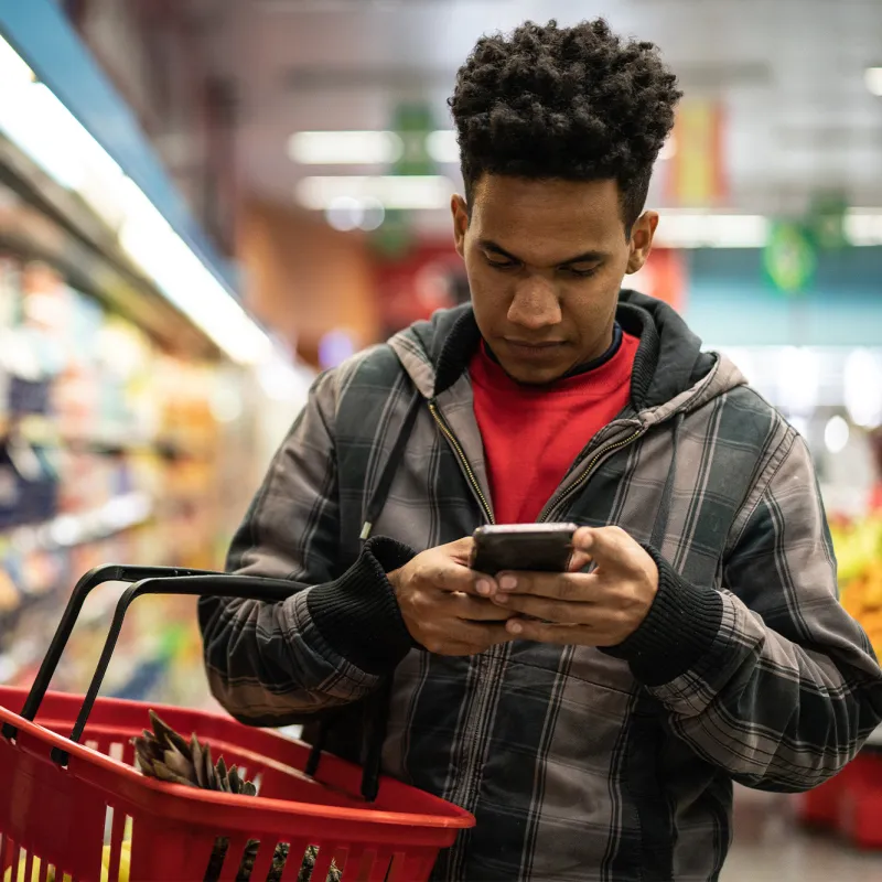 Man looking at his phone while grocery shopping.