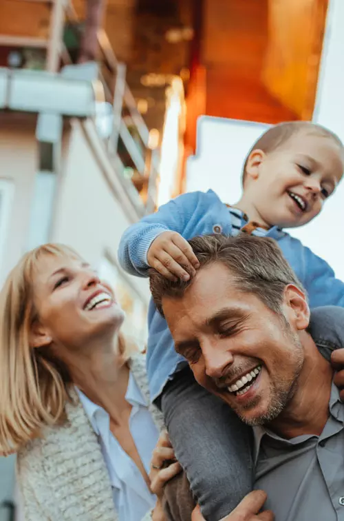 Smiling Parents with Son on Father's shoulders outdoors