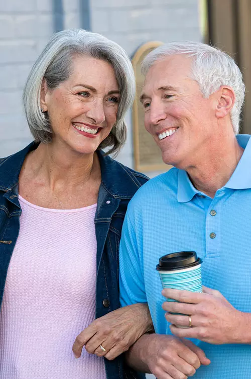 Older couple walking with coffee